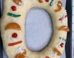 Step <p>Pongalo en la bandeja del horno con papel vegetal, pinte con huevo batido, decore con frutas escarchadas , láminas de almendra, virutas de chocolate. Deje reposar en la bandeja hasta que doble su volumen. </p><p><br></p><p><br></p> illustration